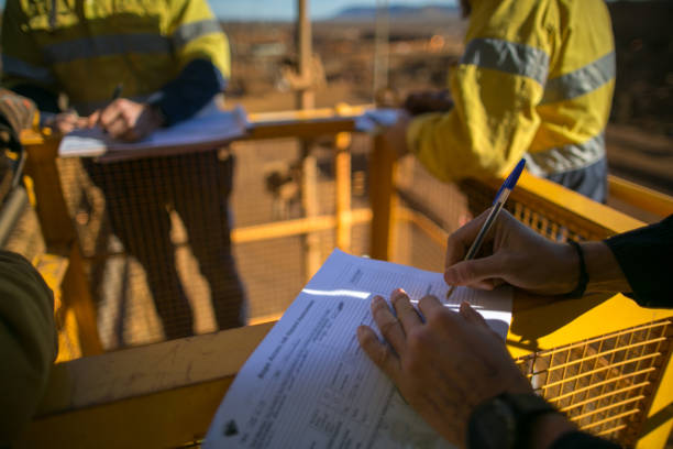 Miner supervisor checking reviewing document before issued sigh of working at height permit JSA risk assessment on site prior to performing high risk work on construction mine site, Perth, Australia