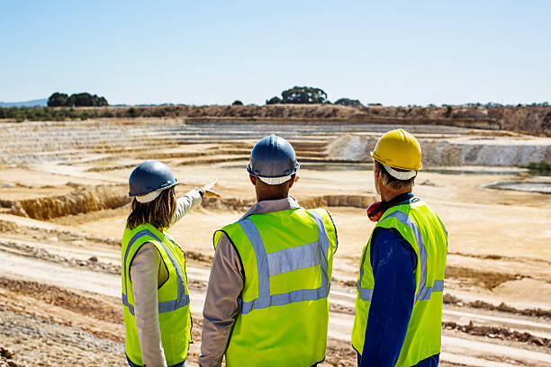 Architects and construction worker examining quarry against clear sky Architects and construction worker examining quarry against clear sky