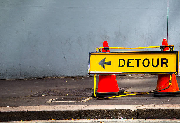 Yellow Direction sign for detour on the footpath, way finding signs to assist people and visitors find their way as easy.