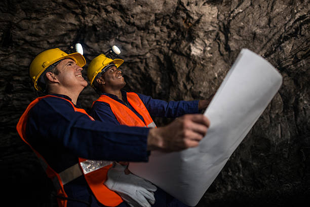 Miners working at the mine underground holding a blueprint - mining Miners working at the mine underground holding a blueprint - mining