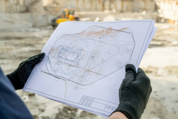 Gloved hands of builder holding paper with sketch of construction Gloved hands of builder holding paper with sketch of construction